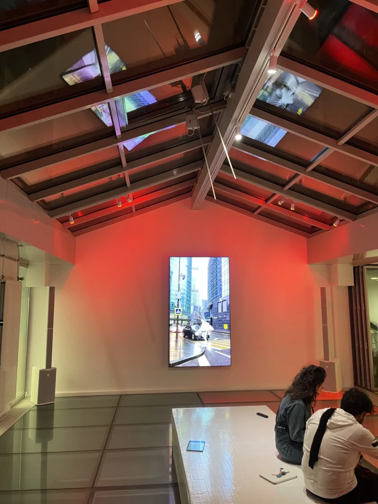 Salle de l’exposition Jenna Marvin baignée de lumière rouge avec écran vidéo – Pandora Event